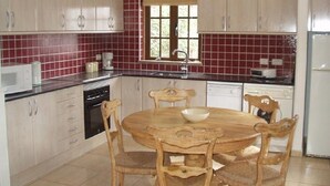A kitchen with wooden cabinets, a round dining table, and chairs. - Villa 83 on the complex of Las Brisas  (Playa Blanca)