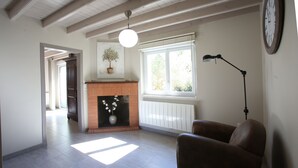 Una sala de estar con chimenea, un sofá, una lámpara y un reloj en la pared.