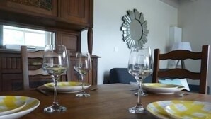 Una mesa de comedor con cuatro copas de vino, platos, un espejo y sillas de madera.