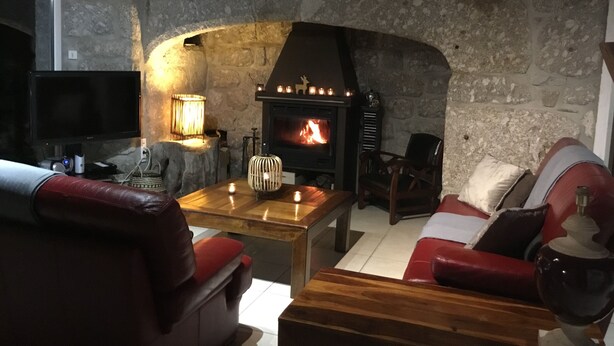 Un salon chaleureux avec une cheminée en pierre, des canapés en cuir et une table basse en bois.