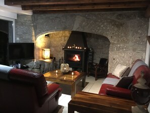 Una sala de estar acogedora con chimenea de piedra, sofás de cuero y una mesa de centro de madera.