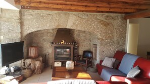 A cozy living room with a stone fireplace, a television, and comfortable seating.
