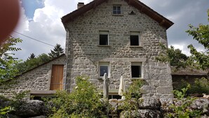 Un bâtiment en pierre avec une porte en bois, deux fenêtres et un petit balcon.