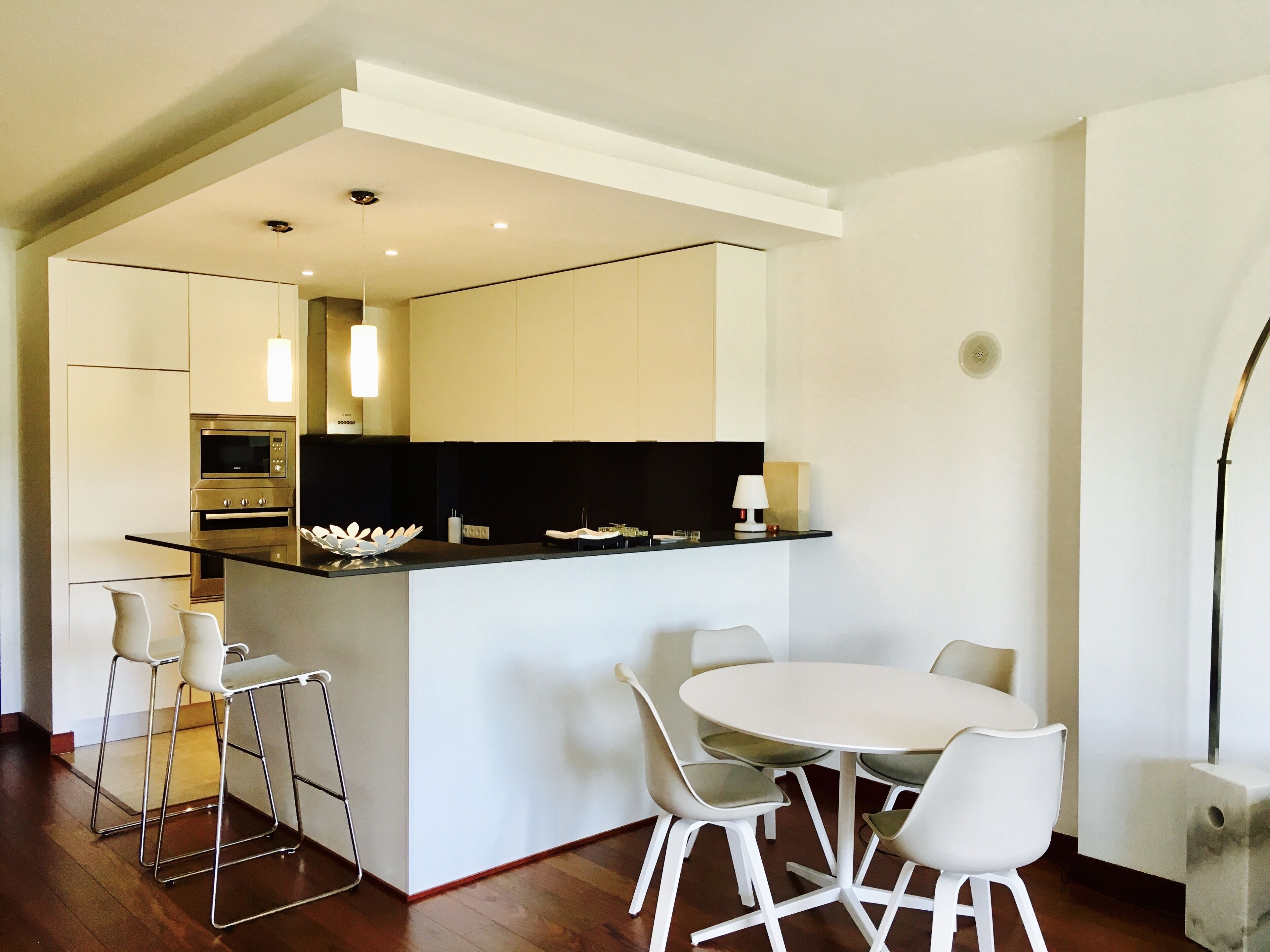 Une cuisine moderne avec un îlot central, des chaises blanches et une table à manger.