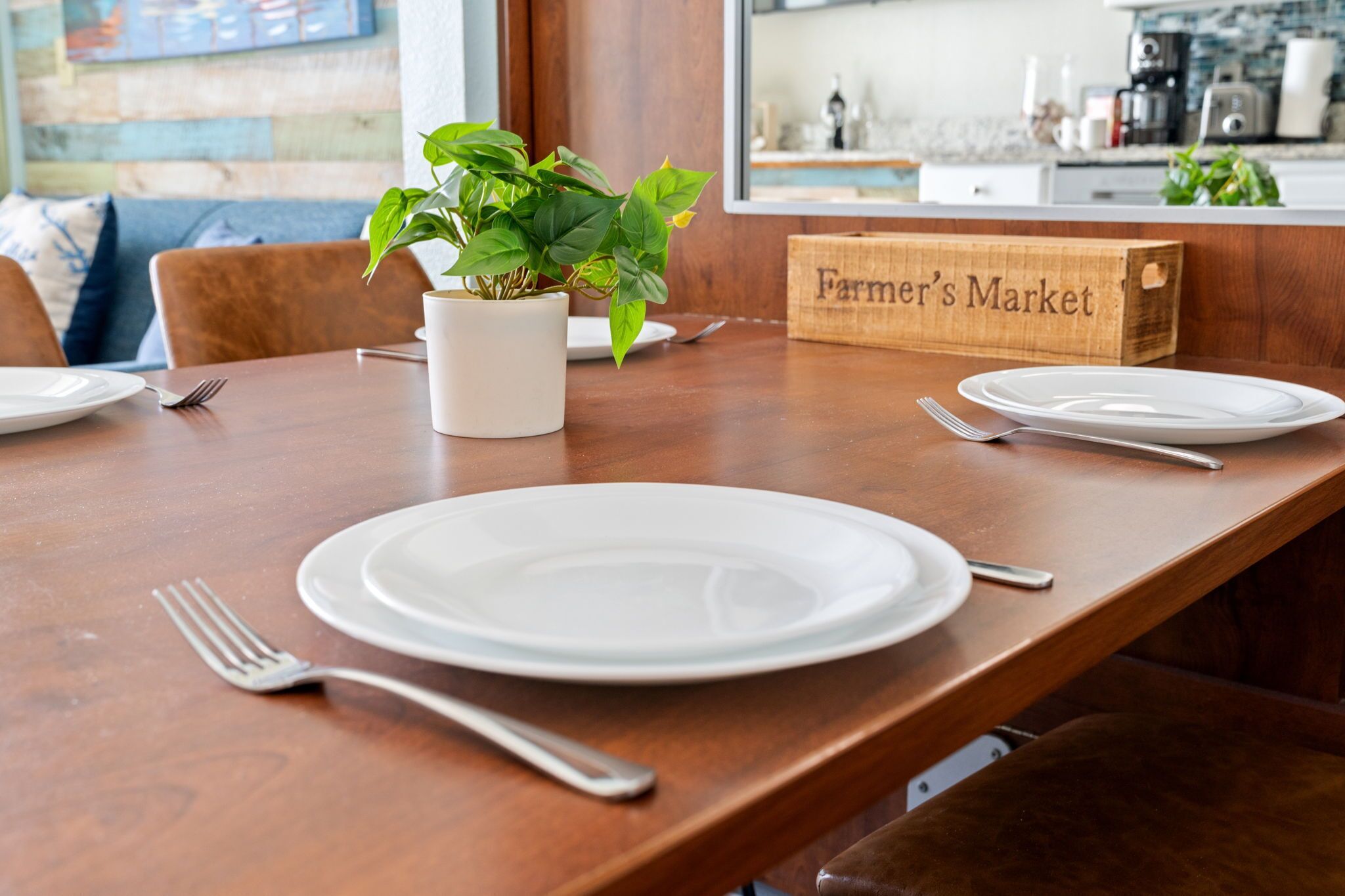 A dining table with white plates, forks, and a potted plant.