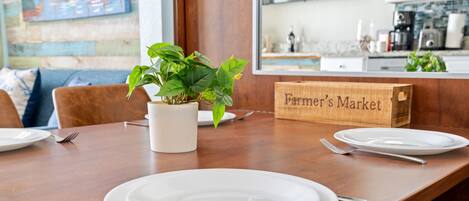 A dining table with white plates, forks, and a potted plant.