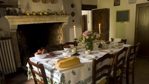 A dining room with a fireplace, a table set for a meal, and a variety of fruits and vegetables on the table. - House-Tower in 15th Century Borgo Fontanini - with mountain views (Zocca)