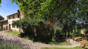 Un edificio de piedra rústica con jardín, mesas al aire libre y un camino de grava.