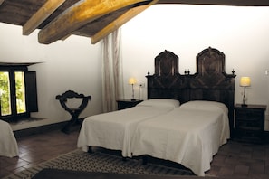 Un dormitorio con dos camas, cabeceros de madera, lámparas de noche y una ventana con cortinas.