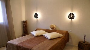 A neatly made bed with a brown bedspread and two pillows, flanked by wall-mounted light fixtures.