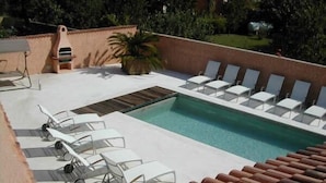 A swimming pool with lounge chairs and a sun umbrella.