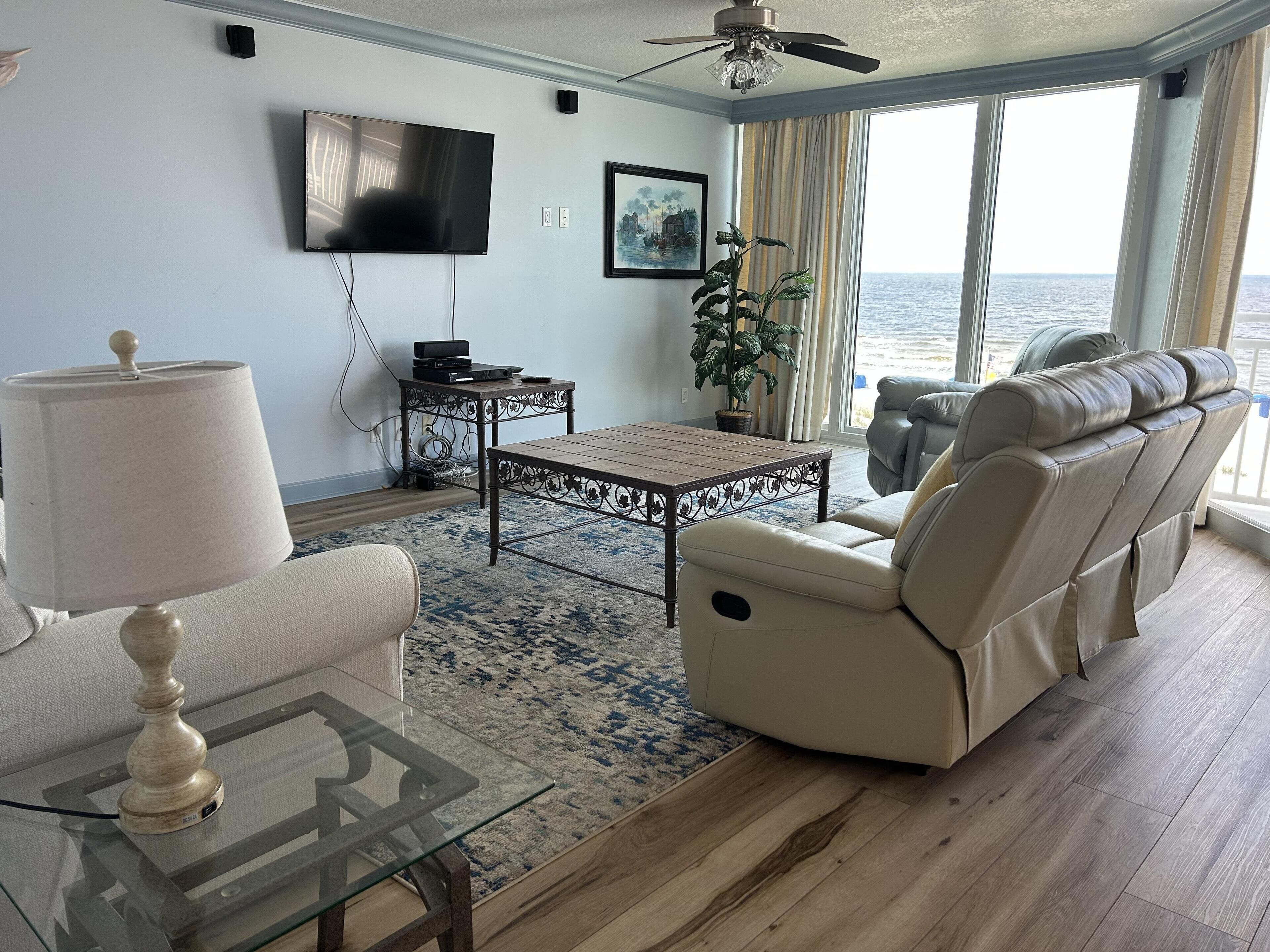 A living room with a sofa, a coffee table, a TV, and a potted plant.