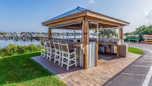 Un belvédère en bois doté d’un bar et de sièges, offrant une vue sur une marina remplie de bateaux.