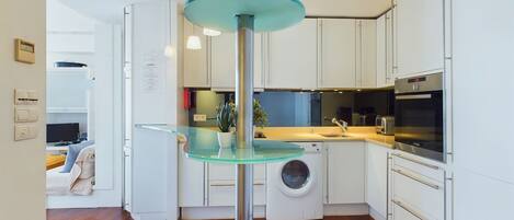 A modern kitchen with white cabinets, a washing machine, and a Bosch oven.