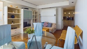 Un moderno salón con una mesa de vidrio para comer, un sofá y una cocina al fondo.
