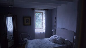 A bedroom with a bed, a chair, a window, and a door.