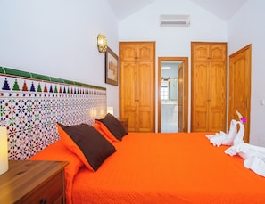 Une chambre avec un grand lit, une armoire en bois et un mur recouvert de carreaux colorés.