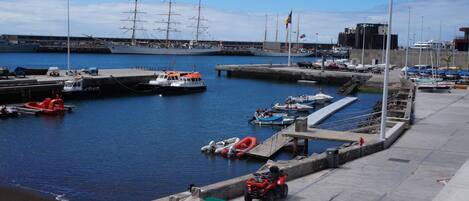 Un puerto deportivo con barcos, un buque grande y un cuatrimoto amarrado.