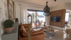 A modern living room with a sofa, a round coffee table, and a TV mounted on a wooden wall.