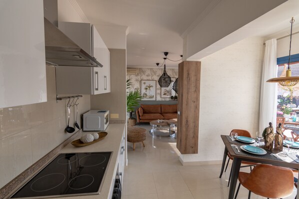 A modern kitchen with a dining area, featuring a central island, a built-in oven, and a dining table with chairs.