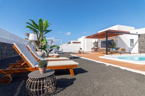A rooftop terrace with lounge chairs, a small pool, and potted plants.
