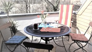 Et rundt udendørs bord med fire stole, et lys og et glas vin.