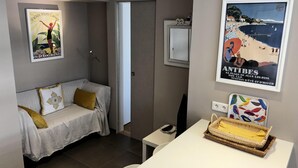 A modern room with a grey sofa, a small table, and a wall with two posters. - Elegance and nice view over Cap D'Antibes and beaches (Antibes)