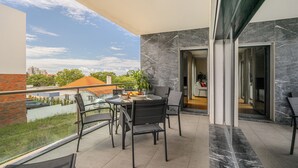 Un balcon avec une table et des chaises, une vue sur la ville et un intérieur moderne agrémenté d’une porte vitrée.