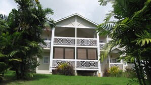 A multi-story hotel with a symmetrical facade, balconies, and lush greenery surrounding the property. - Apartment with Pool set In 70 Acres Of Beautifully Lush Tropical Gardens (Rockley)