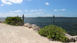 A coastal scene with a sandy beach, rocky outcrops, and calm water.