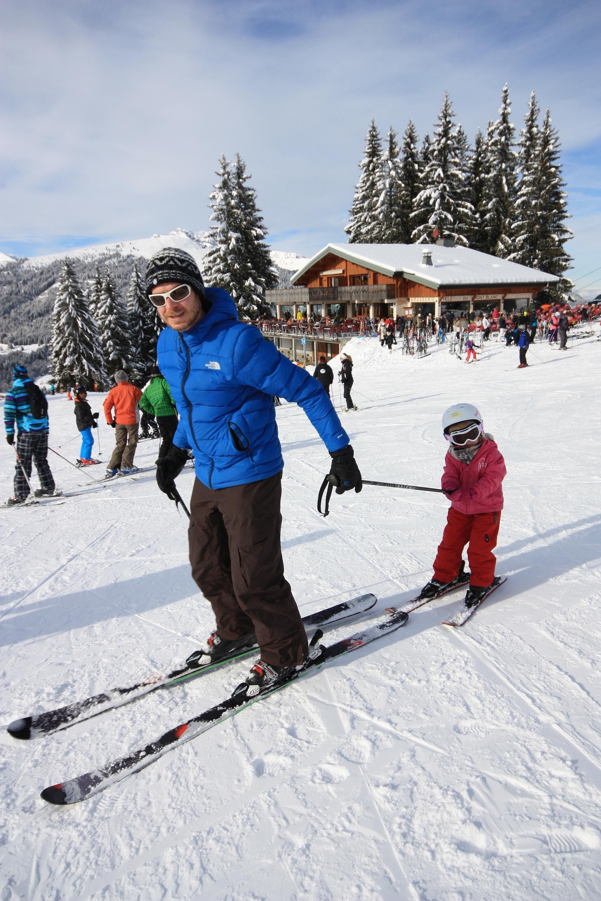 A ski resort with a wooden lodge, snow-covered trees, and skiers on the slopes.