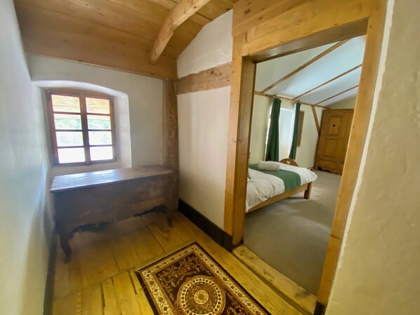 A narrow room with a wooden bench, a window, and a bed with green curtains. - Unique, charming chalet with ensuite rooms, hot tub and games room (Saint-Jean-d'Aulps)
