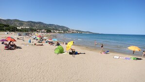 A beach with people sunbathing, umbrellas, and tents.