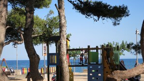 A beach playground with climbing structures and a view of the sea.