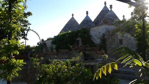 A building with multiple conical roofs and stone walls, surrounded by greenery. - Trullo La Canonica - Itria Valley (Martina Franca)