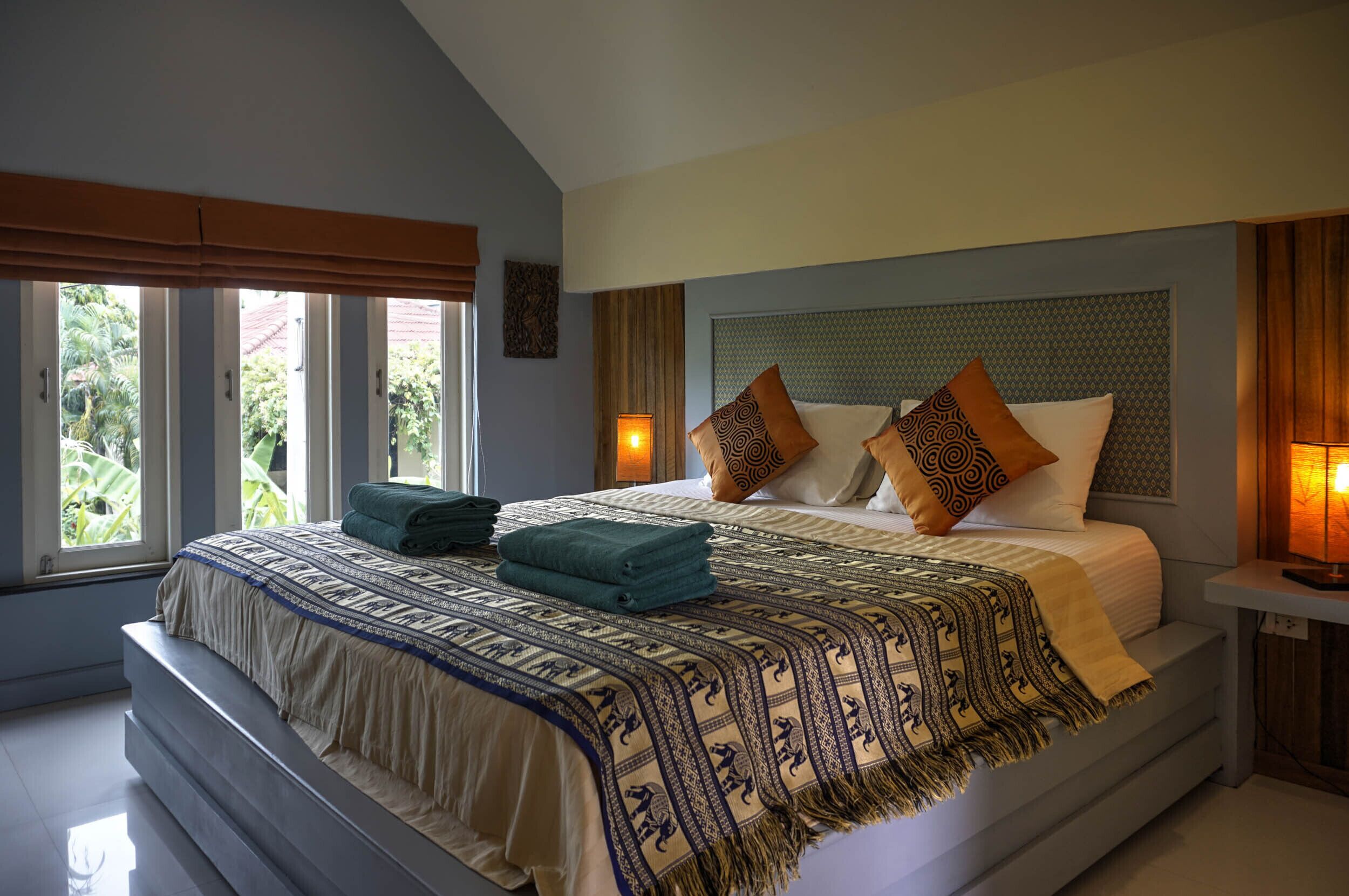 A bedroom with a bed, windows, and a nightstand.