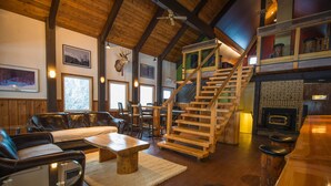 A rustic interior with a wooden staircase, leather seating, a fireplace, and framed pictures on the walls. - One Of A Kind Vacation Rental Located By The Base Of Boulder Mountain! (Columbia-Shuswap B)