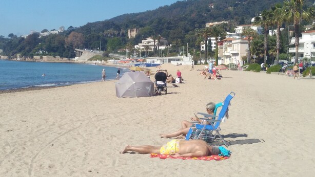 A beach with people sunbathing, umbrellas, and beach chairs. - GOLFE JUAN, 150 m from the beach, F2, bright, 43m2, balcony 14m2, sea view + garage (Vallauris)