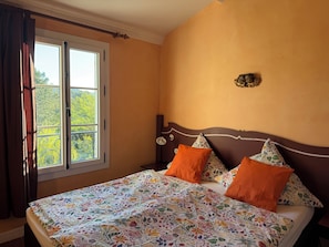 Une chambre à coucher avec un lit, une fenêtre et un luminaire fixé au mur.