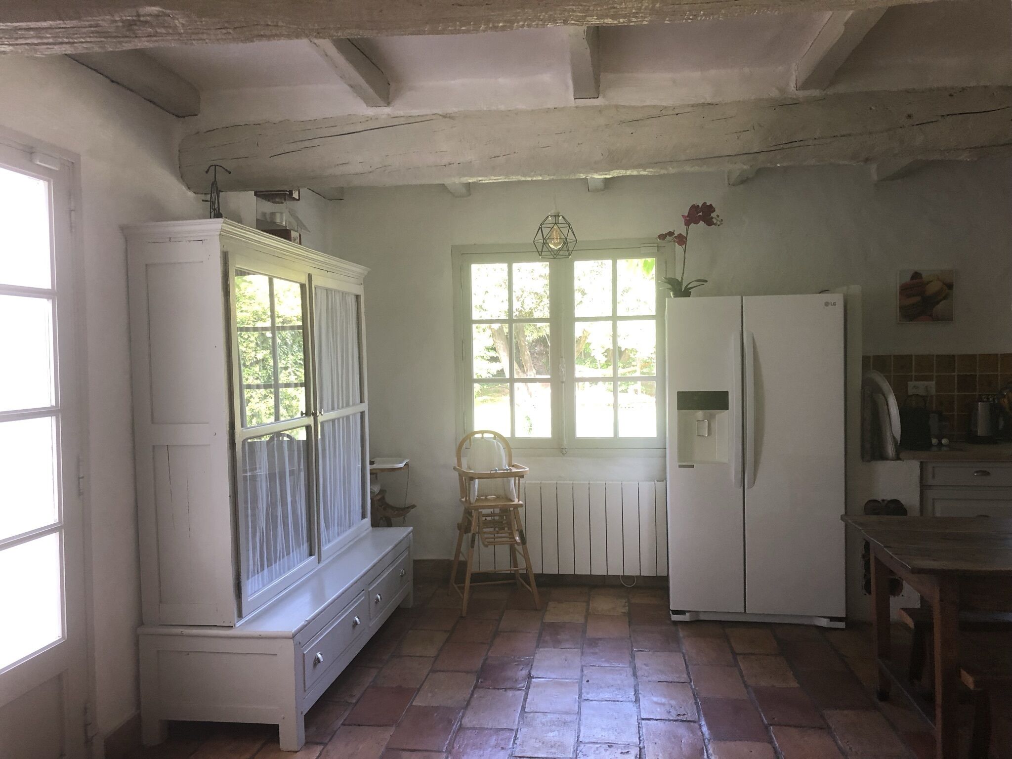Una cocina con un refrigerador blanco, una mesa de madera y un ventanal con vistas a zonas verdes.