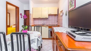 A compact kitchen with a dining area, a television, and a small table with chairs. - Just 200 meters to pebble beach with sea view (Barbariga)