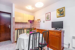 Una cocina funcional con comedor, televisor y una orquídea en maceta.