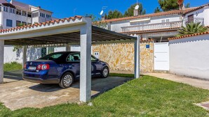 A covered parking area with a blue car parked under a pergola. - Just 200 meters to pebble beach with sea view (Barbariga)