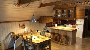 Une cuisine chaleureuse avec des meubles en bois, une table à manger avec des chaises et un coin bar.