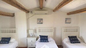 A room with two beds, each with a pillow labeled "MARINA YACHT CLUB". There is a nightstand with a lamp, a small table, and an air conditioning unit on the wall. - Fully restored country villa with pool set in private gardens (Castel Frentano)