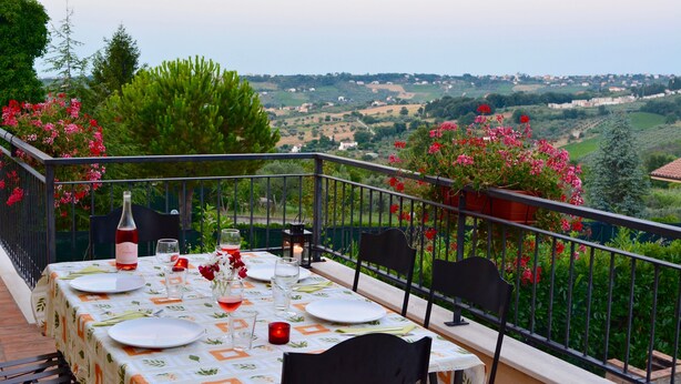 A table set for two with a bottle of wine, glasses, and a candle on a balcony overlooking a countryside view. - Fully restored country villa with pool set in private gardens (Castel Frentano)