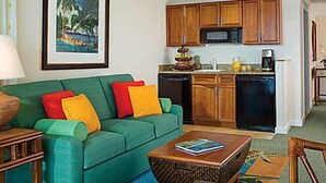 A living room with a green sofa, colorful cushions, a wooden coffee table, and a framed painting on the wall. - Christmas/Xmas and New Year's Weeks 51 & 52 @ Marriot's Maui Ocean Club Hawaii (Lahaina)