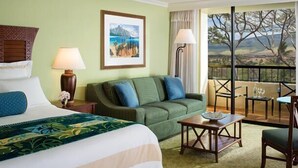 A hotel room with a bed, a green sofa, a small table, and a balcony with a view of trees and mountains. - Christmas/Xmas and New Year's Weeks 51 & 52 @ Marriot's Maui Ocean Club Hawaii (Lahaina)