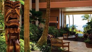 A wooden tiki statue, palm trees, a bench, and a building with balconies. - Christmas/Xmas and New Year's Weeks 51 & 52 @ Marriot's Maui Ocean Club Hawaii (Lahaina)