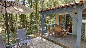 Un espace extérieur abrité doté d’une terrasse en bois, d’un sol en pierre et d’une pergola surmontée d’un toit en tuiles.